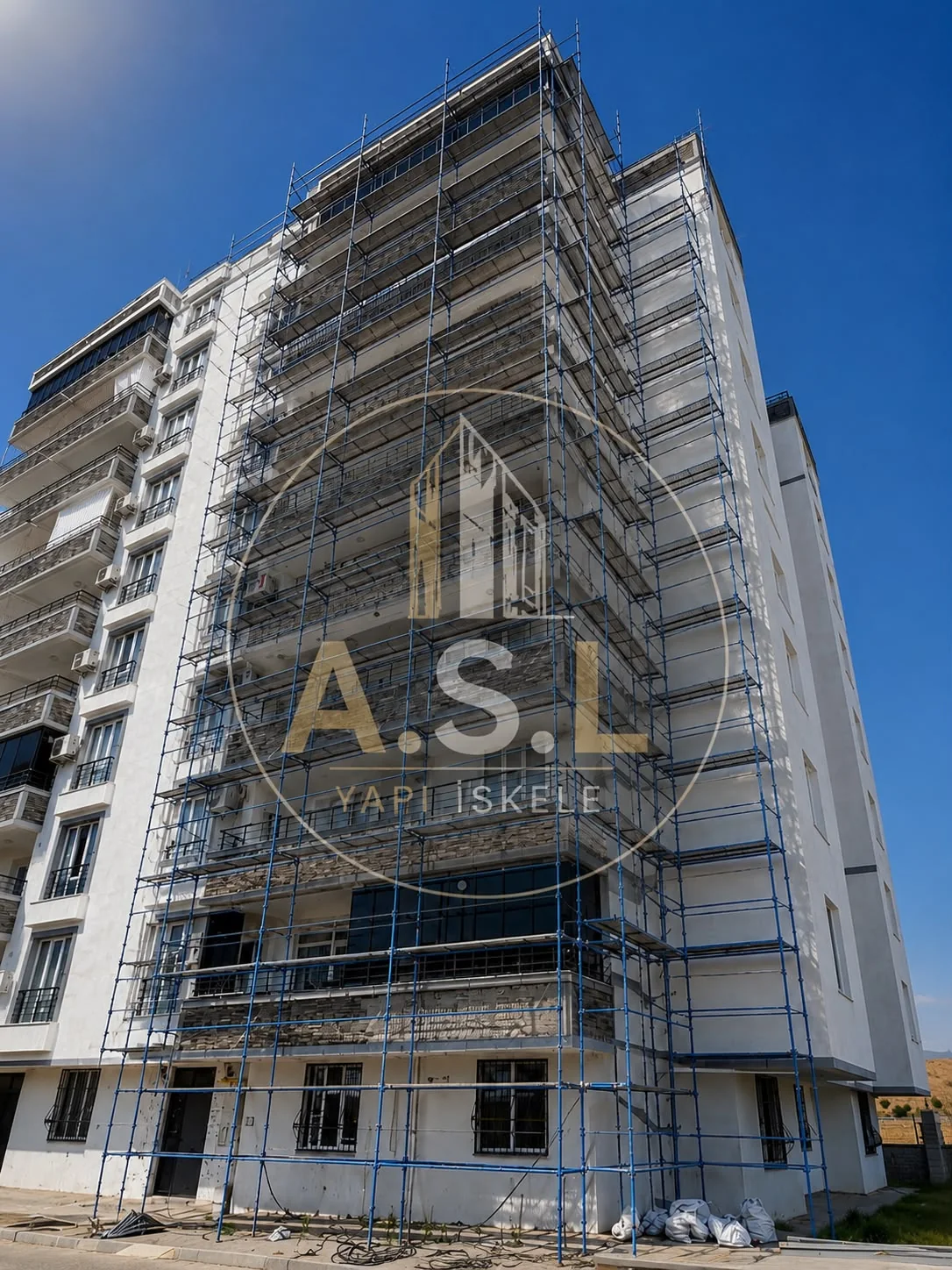 ASL YAPI — Beyaz sıvalı yüksek apartmanın ön yüzü ve köşesinde kurulu mavi cephe iskelesi